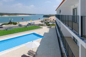 a balcony with a swimming pool next to a beach at Cerca da Vitoria 3 Milfontes in Vila Nova de Milfontes
