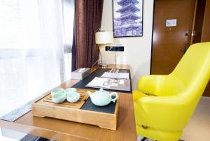 a living room with a yellow chair and a table at Ramada Encore Wuhan in Wuhan