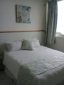 Schlafzimmer mit einem weißen Bett und einem Fenster in der Unterkunft Margate Boulevard 302 in Margate