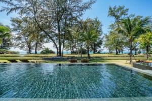 a swimming pool at a resort with trees in the background at Baan Mai Khao in Mai Khao Beach