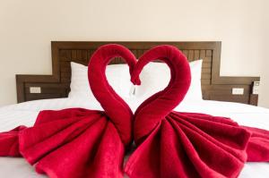 two red towels in the shape of hearts on a bed at Sleep In Lanta Resort in Ko Lanta