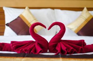 two red velvet swans making a heart on a bed at Sleep In Lanta Resort in Ko Lanta