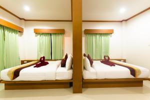 two beds in a room with green curtains at Sleep In Lanta Resort in Ko Lanta