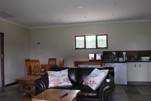 a living room with a black couch and a table at Misty Cottage in Dullstroom