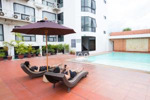 two people laying in lounge chairs next to a swimming pool at CH Hotel in Chiang Mai