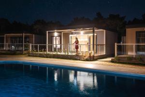 a woman standing on the balcony of a house at night at Mobile Homes Camping Santa Marina, Lanterna in Poreč