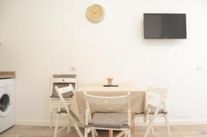 einen Esstisch mit Stühlen und eine Uhr an der Wand in der Unterkunft Apartamentos El Marinero - Roque in Caleta de Sebo