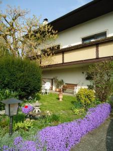 um jardim com flores roxas em frente a uma casa em Ferienwohnung Sick em Uhldingen-Mühlhofen