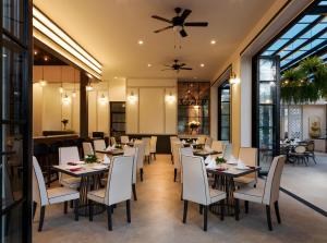 a dining room with tables and white chairs at Chanalai Romantica Resort - Adults Only, Kata Beach in Kata Beach