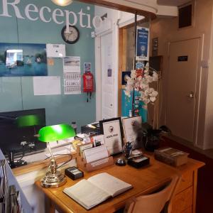 escritorio con ordenador y lámpara verde en Hostel River en Pori