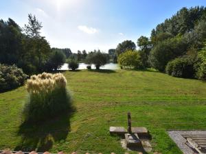 a field of grass with a lake in the background at Beautiful holiday home with sauna in Saint-Omer