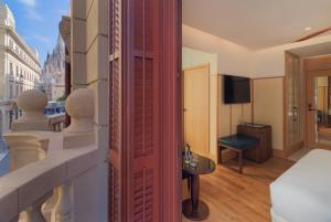 a room with a balcony with a bed and a television at H10 Madison 4* Sup in Barcelona