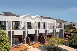 an apartment building with balconies and tables and chairs at Caybeach Papagayos in Playa Blanca