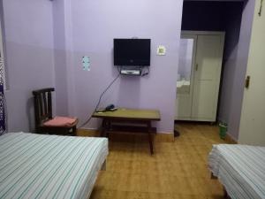 a room with two beds and a desk and a tv at Hotel Kameng in Itānagar