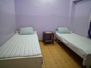 two beds in a small room with a table at Hotel Kameng in Itānagar