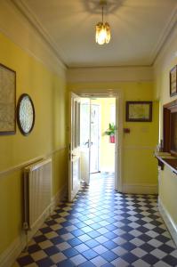 ソールズベリーにあるビクトリア ロッジ ゲストハウスの黄色の壁と白黒のチェッカーの床の廊下