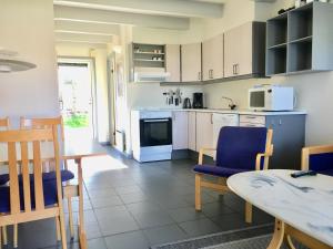 a kitchen with a table and blue chairs and a table and a dining room at Feriecenter & Vandland Øster Hurup in Øster Hurup