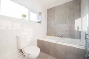 a white bathroom with a toilet and a bath tub at 'Modern Living in Old Town Stratford-upon-Avon' in Stratford-upon-Avon +9 photos
