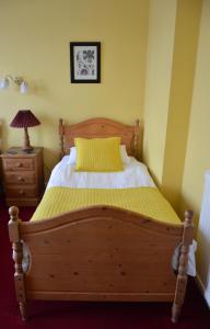 a bedroom with a wooden bed with a yellow pillow at Victoria Lodge Guest House in Salisbury