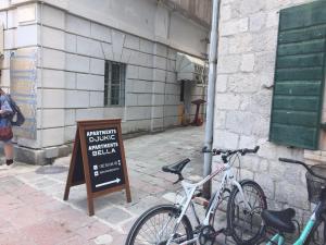 two bikes parked next to a sign in front of a building at Apartments Bella in Kotor
