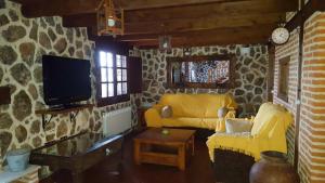 un soggiorno con divano giallo e TV di Casa Rural Refugio Los Perdigones a El Arenal