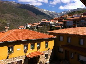 Casa Rural Sierra de Tormantos في Guijo de Santa Bárbara: مجموعة مباني فيها جبال في الخلف