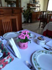 una mesa con platos y un jarrón de flores. en Albergo La Meridiana, en Portogruaro