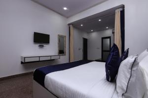 1 dormitorio con 1 cama grande y TV en la pared en Hotel Vizima Palace - NEAR WAVE CITY CENTER METRO STATION, en Noida