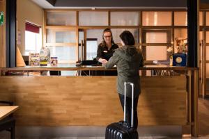 deux femmes debout au comptoir avec leurs bagages dans l'établissement Hotel Restaurant Zalen Hoogeerd, à Niftrik