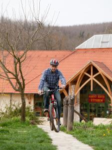 een man op een fiets op een stoep bij Somogy Kertje Üdülőfalu és Étterem in Bonnya