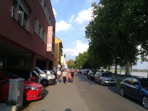 een groep mensen die door een straat lopen met geparkeerde auto's bij Guesthouse Sava in Slavonski Brod