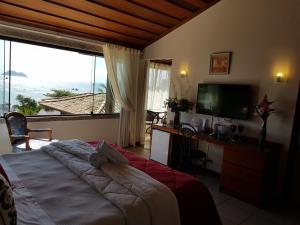 Dormitorio con cama, escritorio y TV en Coronado Beach Hotel, en Búzios