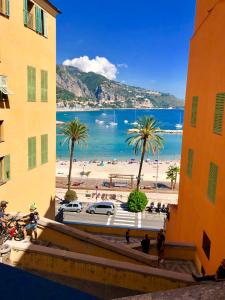 a view of a beach with palm trees and the ocean at Les Sablettes in Menton