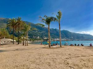 a group of people on a beach with palm trees at Les Sablettes in Menton
