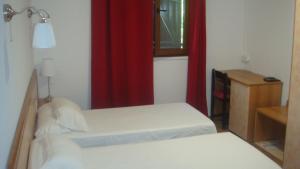 ein Schlafzimmer mit 2 Betten und einem roten Vorhang in der Unterkunft Le FLORIDA in Zicavo