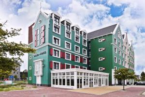 a large building with green and white at Zaan Hotel Amsterdam - Zaandam in Zaandam