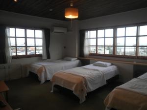 a hotel room with two beds and two windows at Orange Pension in Gamagōri