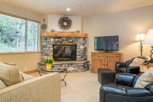 a living room with a stone fireplace and a television at Bridgepoint 13 in Ketchum