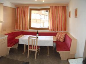 una sala da pranzo con tavolo e divano rosso di Appartements Hirner a Fügen