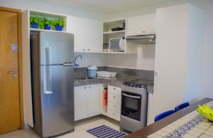 a kitchen with a stainless steel refrigerator and white cabinets at Flat Luxo Praia dos Carneiros in Praia dos Carneiros