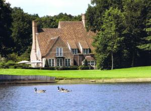 three ducks swimming in the water in front of a house at Bossenstein Golf & Polo Club in Ranst