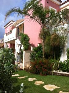 ヴィッラシミーウスにあるCasAntonioの庭のヤシの木があるピンクの家
