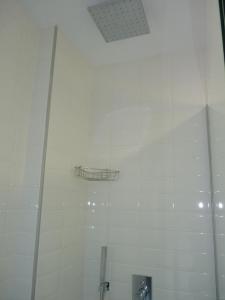 a white tiled shower with a shelf on the wall at Los Calaos de Briones in Briones