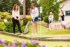 Duas mulheres estão a jogar golfe num jardim. em Kronocamping Lidköping em Lidköping