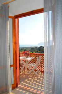una puerta abierta a un balcón con mesa y sillas en Elbamar Lacona en Lacona