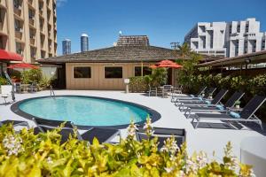 a swimming pool with lounge chairs and umbrellas at Pagoda Hotel in Honolulu