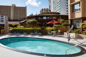 a swimming pool with chairs and a table and buildings at Pagoda Hotel in Honolulu