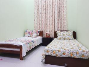 a bedroom with a bed and a chair and curtains at Islamic Homestay Sungai Petani in Sungai Petani