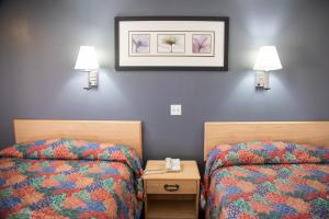 a room with two beds and two lamps on the wall at Travel Inn in Phoenix