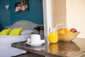 a table with a bowl of fruit and a glass of orange juice at Le Neoulous in Le Boulou